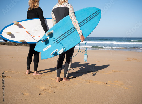 Photography 2 Unrecognizable surfer females watching the waves on the beach