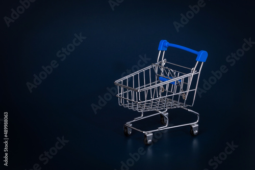 mini shopping cart on blue background and copy space