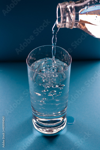 water pours from a bottle into a glass on a blue background, top view