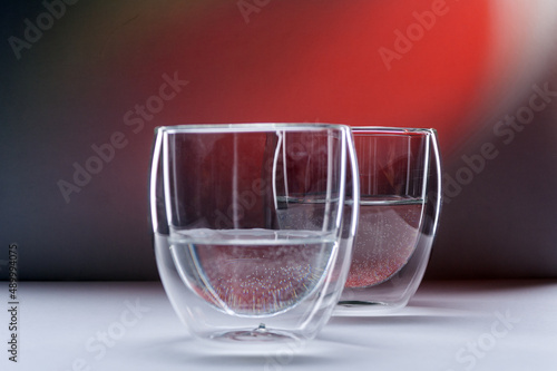 two glasses with water on a red background with copy space