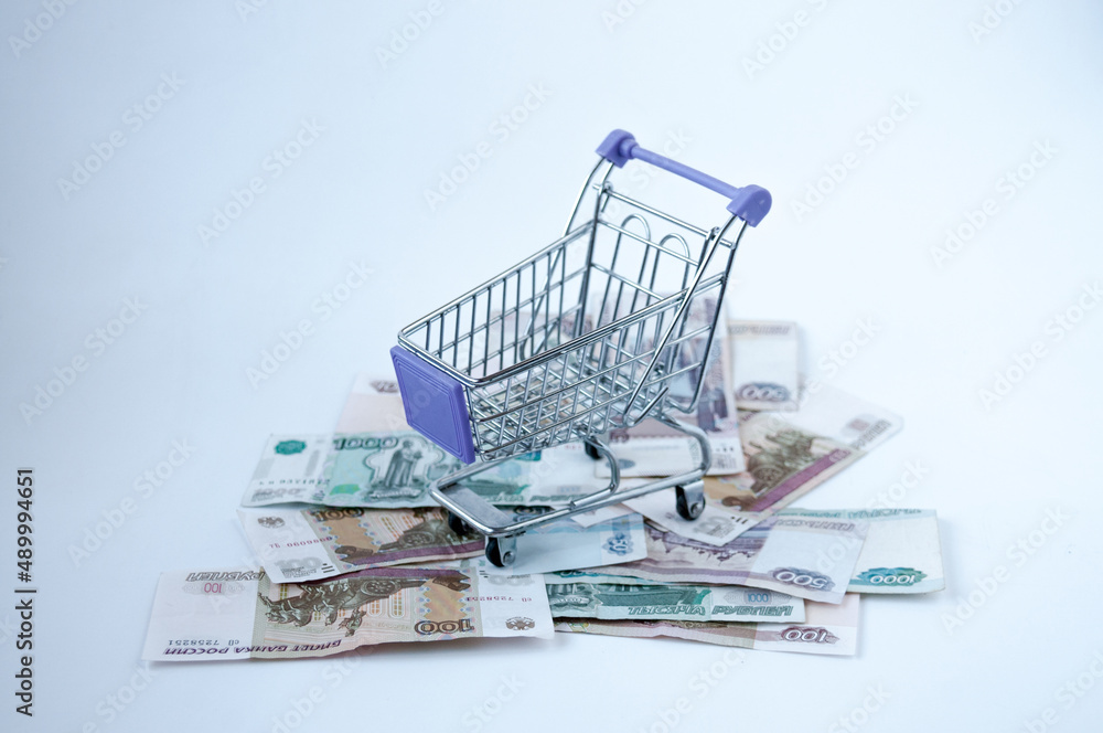 A grocery iron cart stands on Russian rubles on a light background