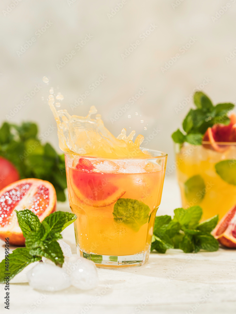 Fresh orange juice in a glass with splashes and drops. Summer refreshing and healthy dessert.