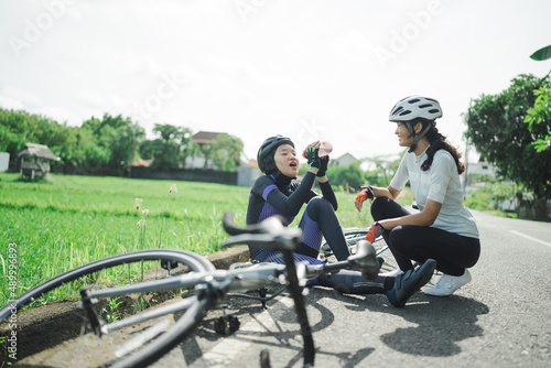 woman cyclist giving a bottle of water to her friend's