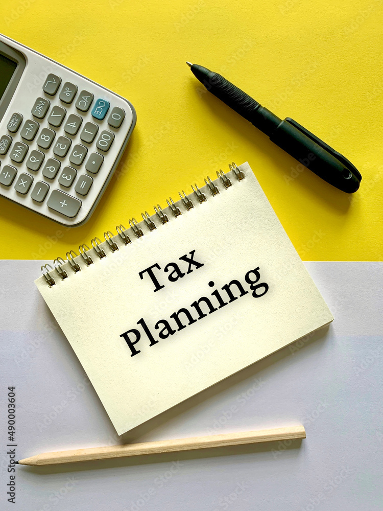 Tax planning text on notepad with calculator and pen background. Business concept. Tax planning text on notepad with calculator and pen background. Business concept.