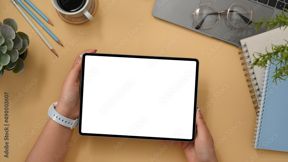 Obraz premium Comfortable workspace with office accessories and female holding tablet