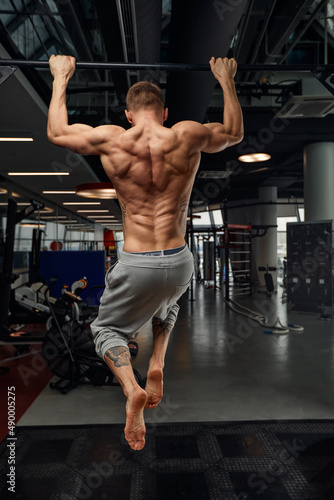 Muscular strong man exercising in the sport gym, Man doing horizontal push-ups with bars in gym. Background gym with copy space.