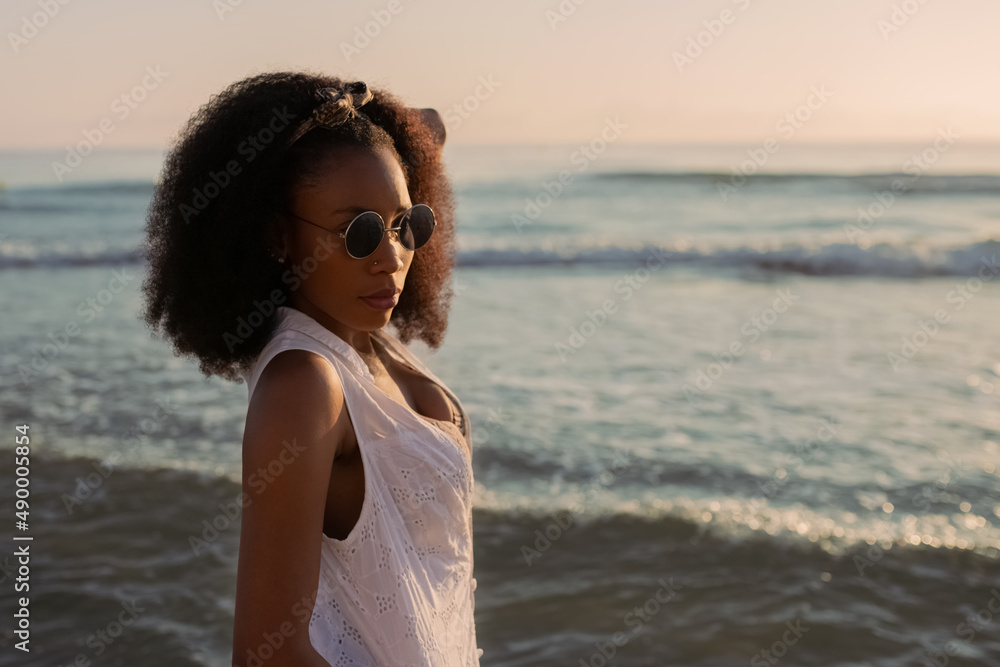 Portrait of an african woman in the beach posing and looking at camera at sunset Portrait of an african woman in the beach posing and looking at camera at sunset