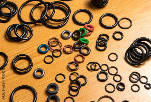 Black hydraulic and pneumatic o-rings in different sizes on a wooden background. Sealing rings for hydraulic connections. Rubber seals for plumbing. photo