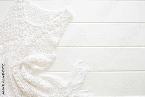 A white knitted dress lies on a white wooden deck chair. Swimwear, leisure wear. Vacation concept on the beach, with copy space and place for text.