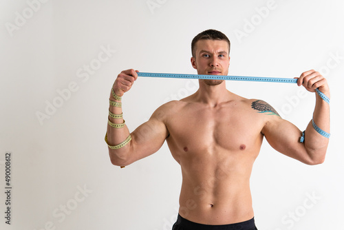 A man measures the waist of a metre and poses against a white background isolated body hand, torso girl athletic slimming weight, ifestyle Weight studio, portrait sport attractive tape photo