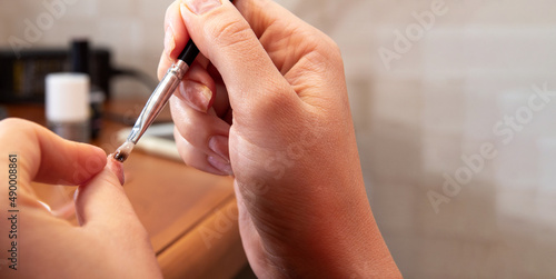 Applying gel to the thumbnail. Close-up. The process of self-manicure. Image for beauty websites. Selective focus.