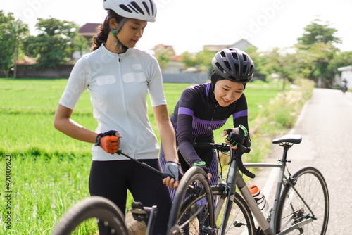 asian cyclist using pocket pump to pump her bicycle flat tire