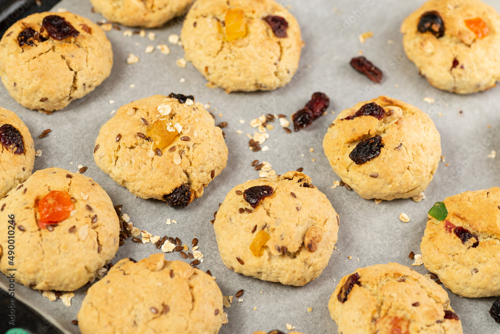 Refrigeration of freshly baked soft oatmeal cookies with raisins, candied fruits, flax and sesame seeds and walnuts on baking paper Refrigeration of freshly baked soft oatmeal cookies with raisins, candied fruits, flax and sesame seeds and walnuts on baking paper