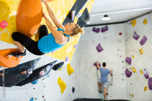 Caucasian woman exercising on wall in climbing gym during bouldering training.