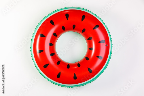 Top view closeup isolated studio shot of colorful red and green watermelon with black seeds round shape swimming pool lifesaver kid rubber ring using on sea beach vacation placed on white background photo