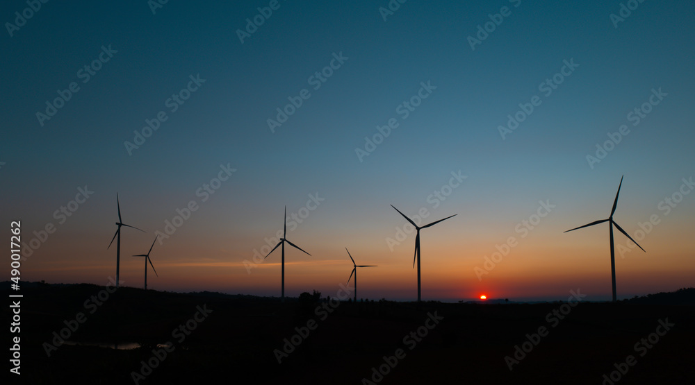 Obraz premium wind turbine field at beautiful sunset sky background. renewable energy