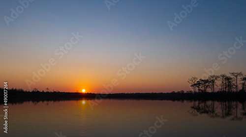 sunrise at coast of the lake. Blue sky and sun reflection on water. Nature landscape in asian.