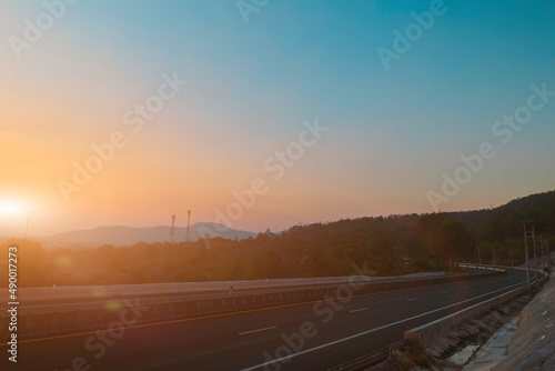 Asphalt road and mountain landscape at sunset sky background. Country road and mountains.