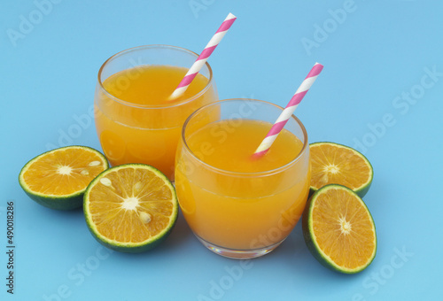 Fotografía Glasses of fresh orange juice with drink straws and green orange fruits slices o