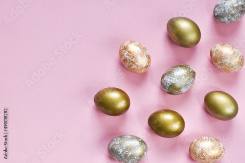 Elegant golden and white Easter eggs painted with dots and stripes on pink background. Copy space, flat lay composition. Happy easter. Greeting card for holiday