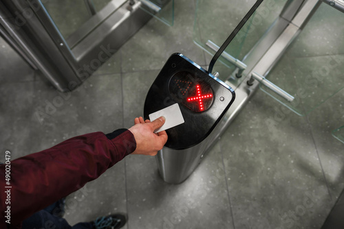 Close up of unrecognizable swiping card passing turnstile to enter building. The hand holds the card. Access denied. photo