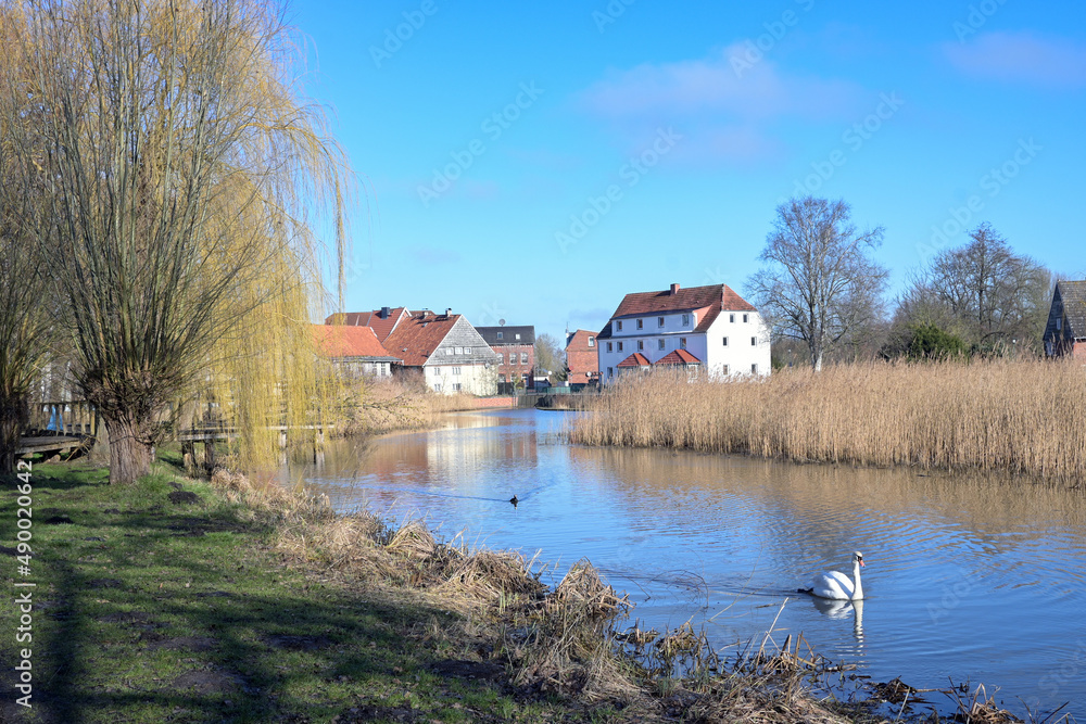 Obraz premium Mill pond of the small town Rehna with park and old town houses against the blue sky in Mecklenburg-Western Pomerania, Germany, copy space