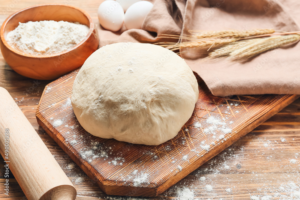 Raw dough with rolling pin on wooden background Raw dough with rolling pin on wooden background