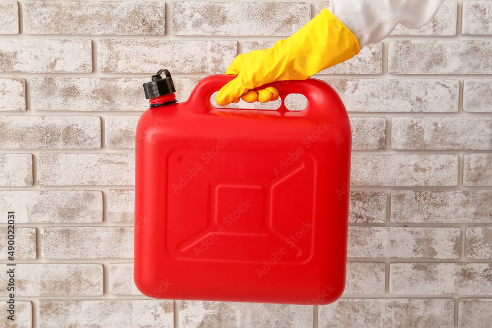 Male hand in rubber gloves holding canister near brick wall Male hand in rubber gloves holding canister near brick wall