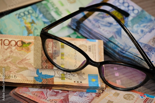 Almaty, Kazakhstan - 12.01.2020 : Glasses are placed on stacks of Kazakhstani tenge banknotes.