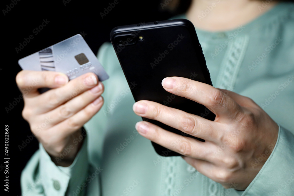 Woman holding smartphone and credit card in hands. Concept of online shopping and payments, blocking transactions Woman holding smartphone and credit card in hands. Concept of online shopping and payments, blocking transactions