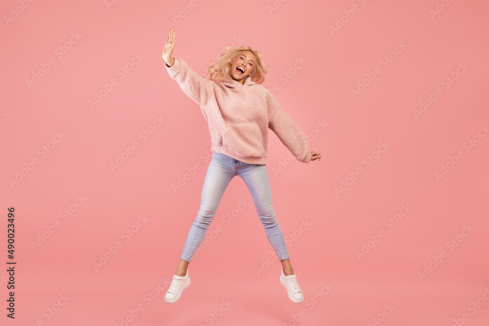 Expressing joy and happiness. Full length shot of active young woman jumping and having fun over pink background