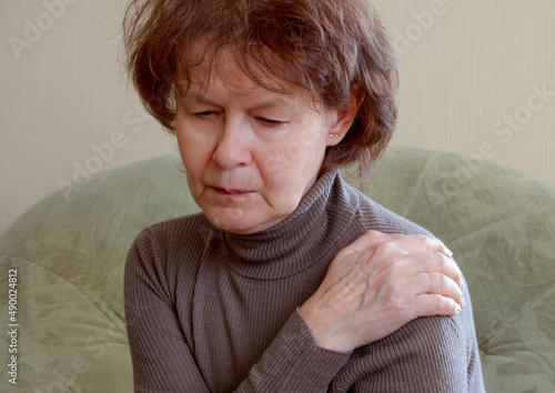 Woman suffering from frozen shoulder (adhesive capsulitis) photo