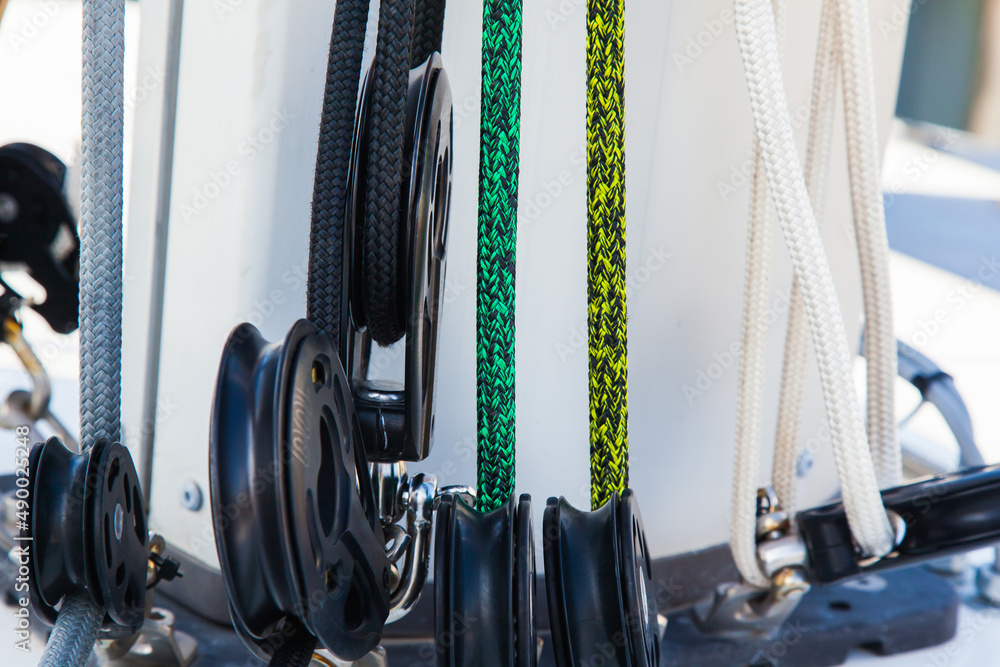 Part of the mast and hull of a sailing yacht, with multi-colored ropes ...