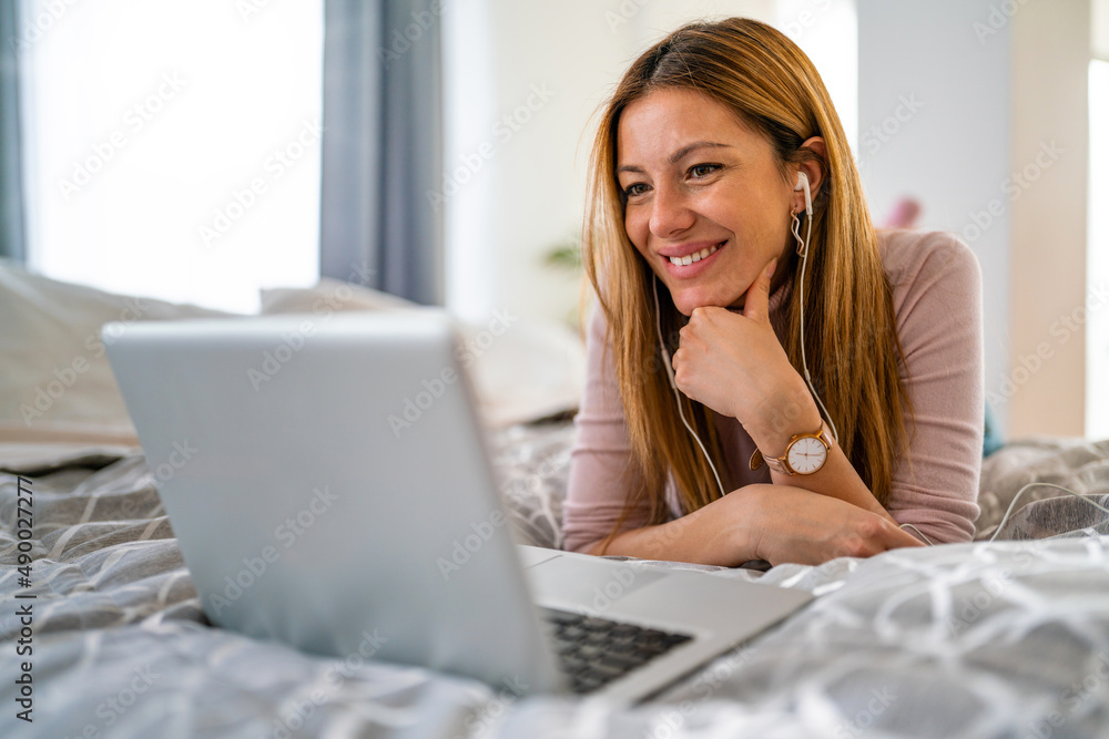 Happy woman working, surfing with laptop on the bed at home Happy woman working, surfing with laptop on the bed at home