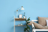 Comfortable sofa, houseplants and modern lamp on table near blue wall
