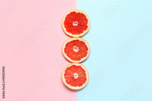 Slices of tasty ripe grapefruit on color background