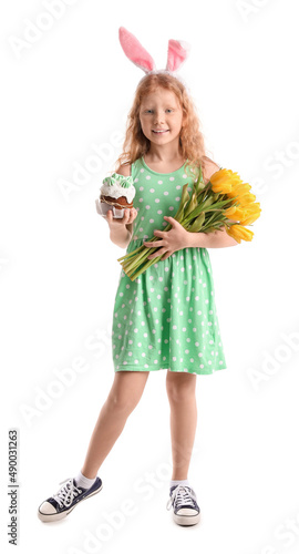 Funny little girl with bunny ears  flowers and Easter cake on white background