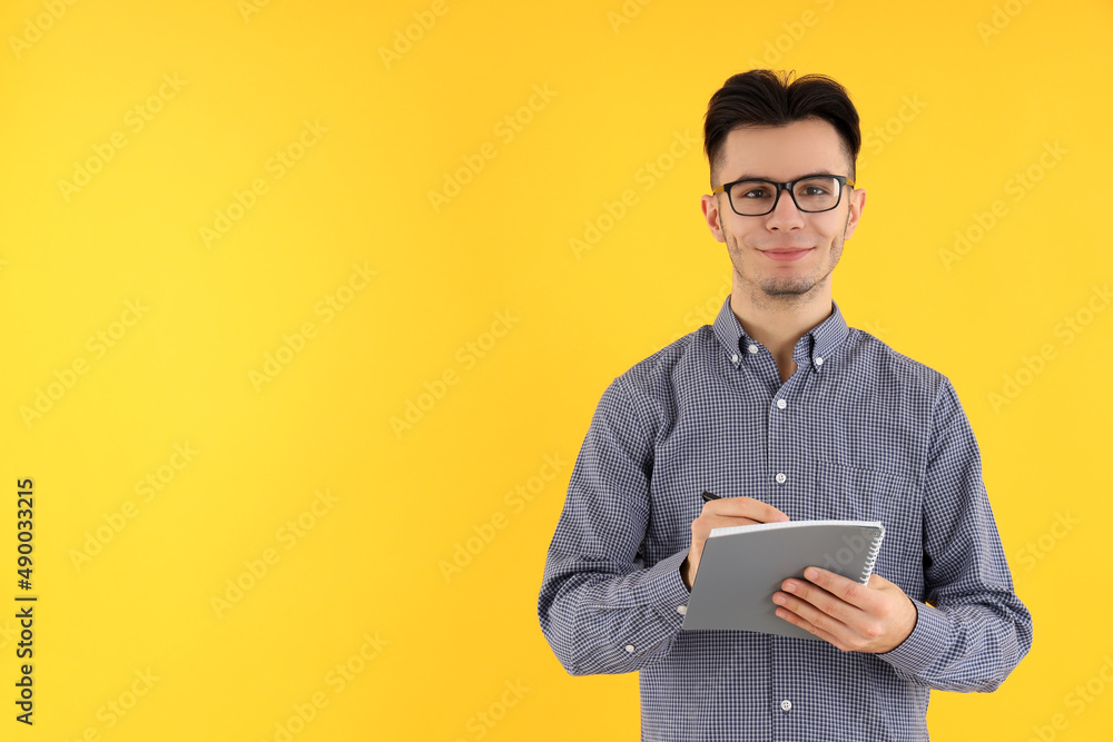 Attractive guy with notebook and pen on yellow background Attractive guy with notebook and pen on yellow background