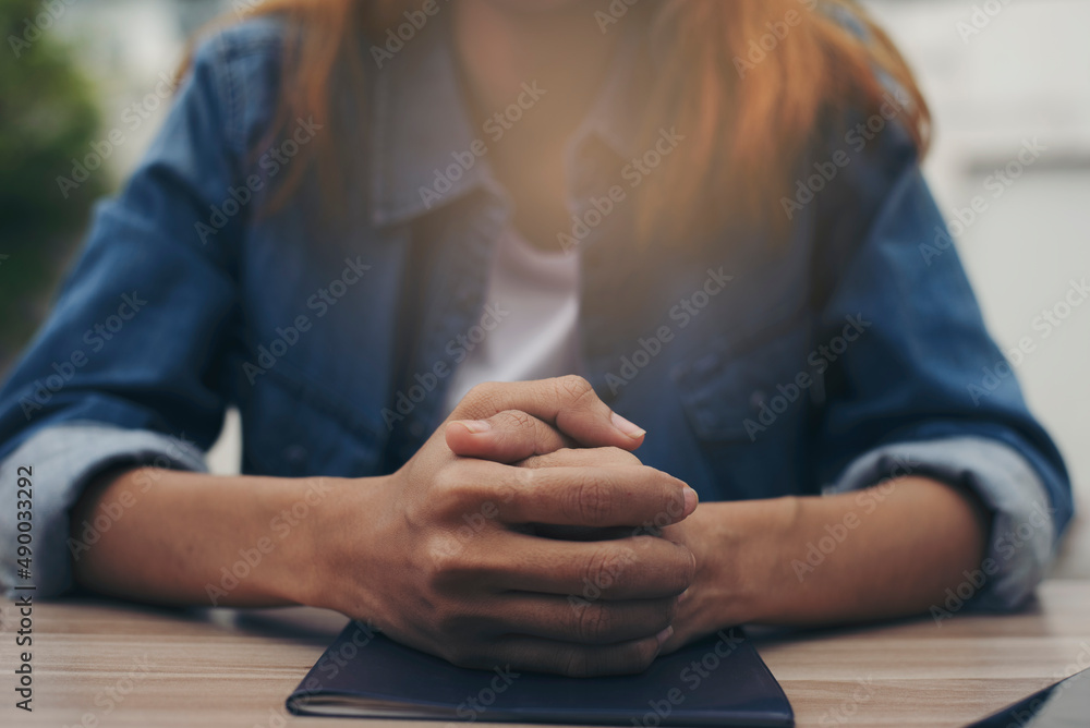Obraz premium Pray and bible concept. Hand in hand together on bible by woman (worship christian), thinking and closed her eyes at church. Person front view, female praying, hope for peace.