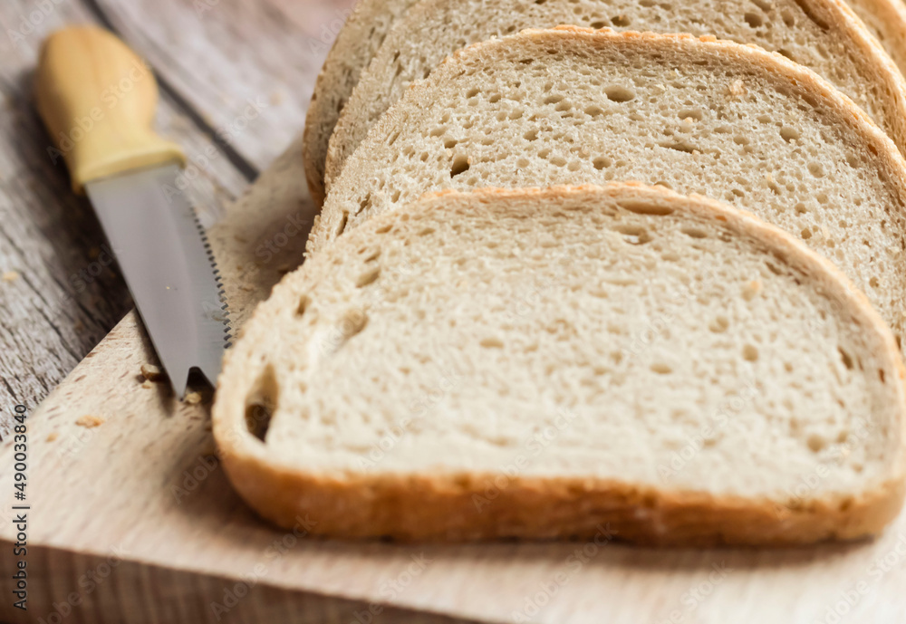 Sliced fresh bread and cutting knife on rustic table Sliced fresh bread and cutting knife on rustic table