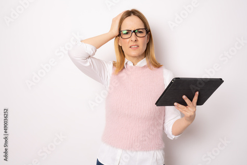 Young pensive business woman holding tablet standing isolated over white background. Business concept.