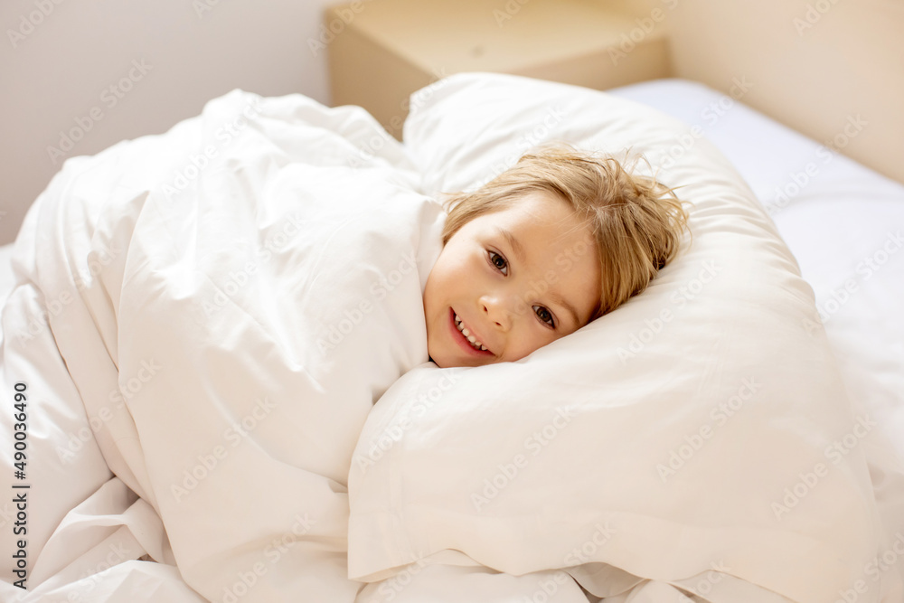Mother and child, blond toddler boy, cuddling in bed in the morning, love and tenderness Mother and child, blond toddler boy, cuddling in bed in the morning, love and tenderness