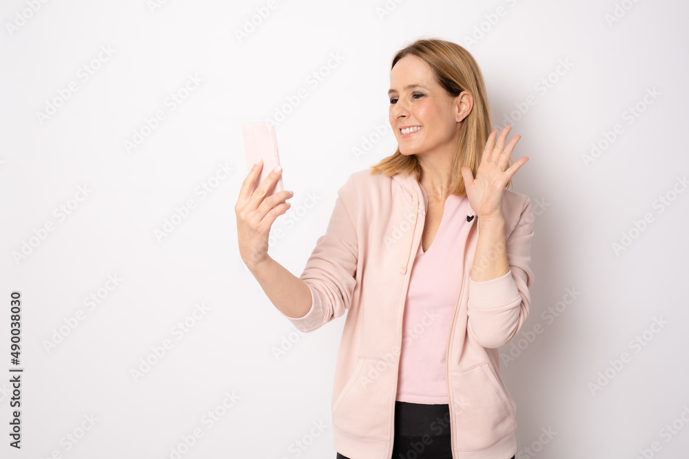 Happy young woman in sports clothing smiling and holding smart phone on white background. Happy young woman in sports clothing smiling and holding smart phone on white background.