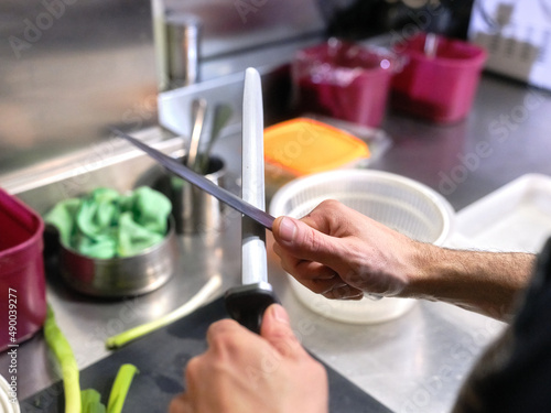 Cook sharpening kitchen knives in a restaurant