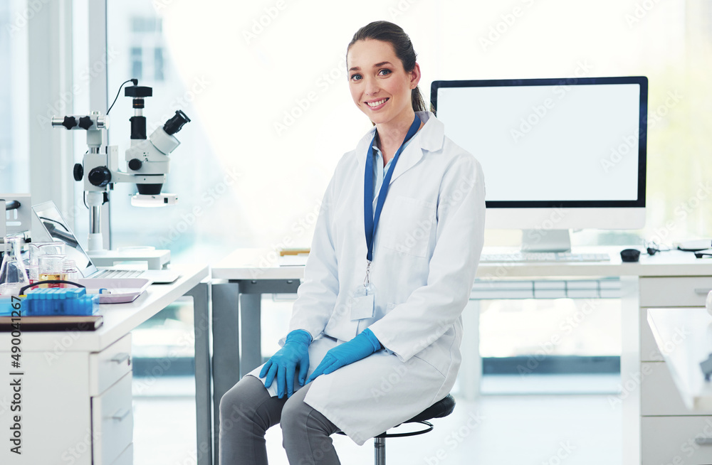 She needs a break. Portrait of a cheerful young female scientist seated at her desk ready to work inside of a laboratory during the day. She needs a break. Portrait of a cheerful young female scientist seated at her desk ready to work inside of a laboratory during the day.