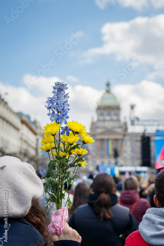 Obraz na plátně Woman activist holds flowers in the colours of the Ukrainian flag during protests against the Russian invasion of Ukraine