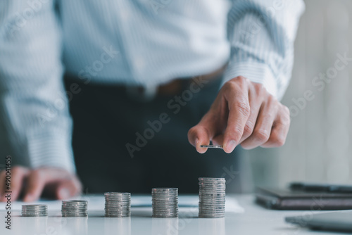 saving money hand businessman putting coins on stack on table in office, concept finance and accounting.