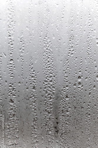 Vertical natural background, condensation on glass with drops flowing down, humidity and foggy blank. Outside , bad weather, rain