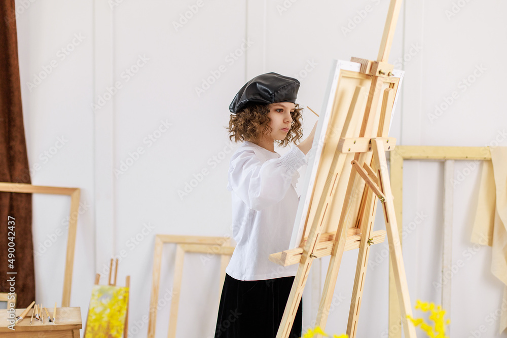 Little girl painting a picture in a studio or art school. Creative pensive painter child paints a colorful picture on canvas in workshop. Talented kids Little girl painting a picture in a studio or art school. Creative pensive painter child paints a colorful picture on canvas in workshop. Talented kids