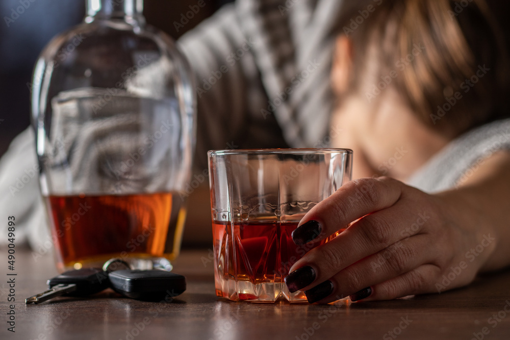 Drunk intoxicated woman sleeping near whiskey glass, female heavy drinker alcoholic passed out lying asleep after booze, alcoholism problem, alcohol addiction concept. Keys from auto lying on table Drunk intoxicated woman sleeping near whiskey glass, female heavy drinker alcoholic passed out lying asleep after booze, alcoholism problem, alcohol addiction concept. Keys from auto lying on table